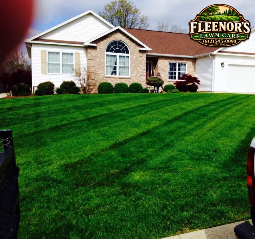 Vivid green mowing stripes in front of a landscaped white and brick home