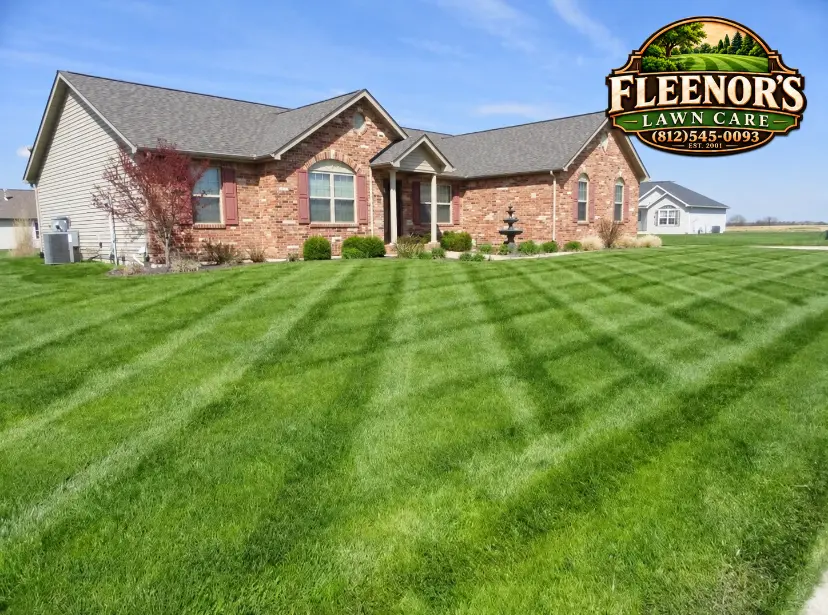 Striped front lawn in front of a brick home with neatly shaped shrubs