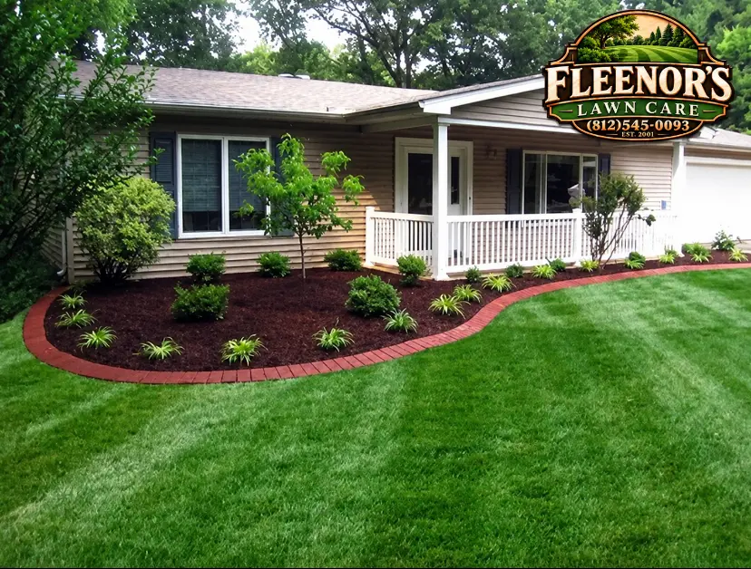 Fresh dark mulch beds with red brick edging and planting beside a home